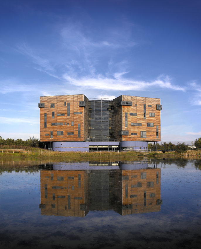 Architectural exterior of a commercial office building over a lake with a mirrored reflection