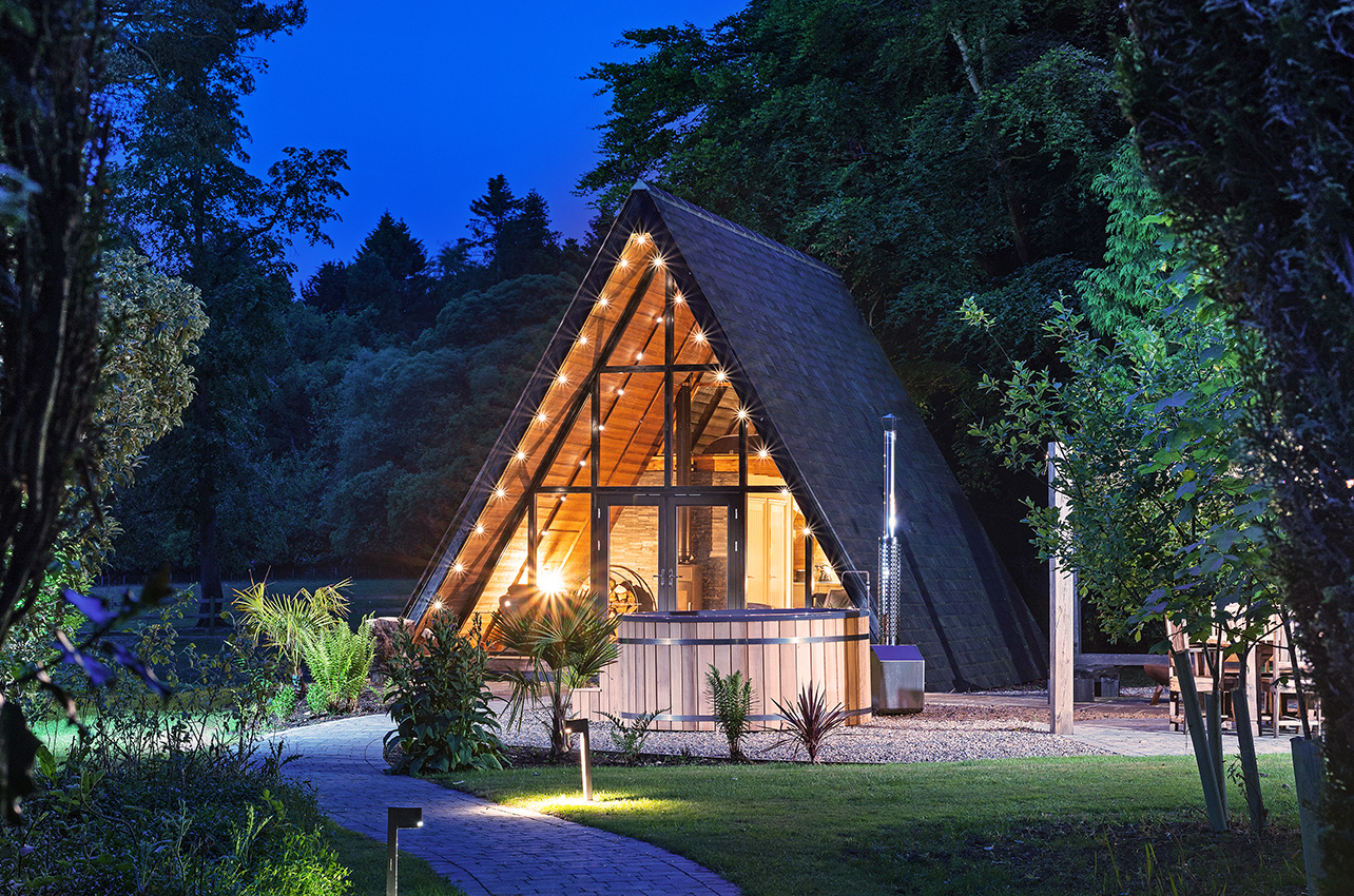 A-Frame garden building with surrounding gardens at dusk