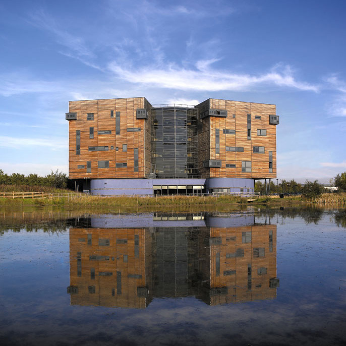 Quadrus Centre wooden clad office buidling in daytime with mirror reflections of the building in lake