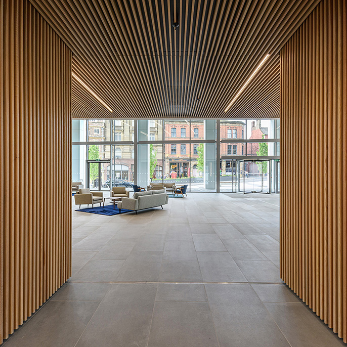 Interior of a commercial office building with wooden design features looking towards a glazed area