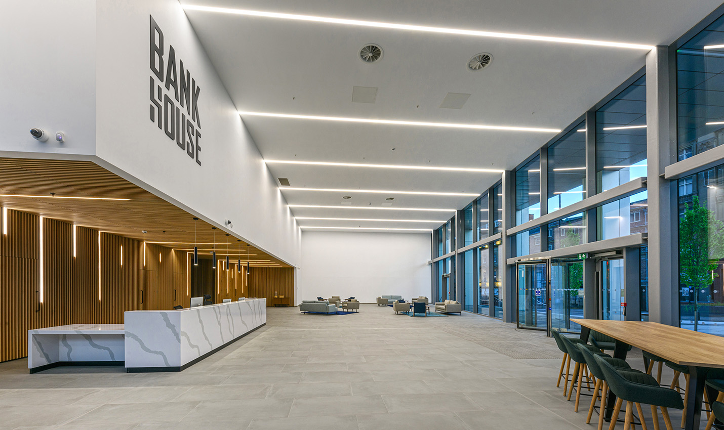 Commercial office reception area with large glazed wall and high ceilings with wooden details