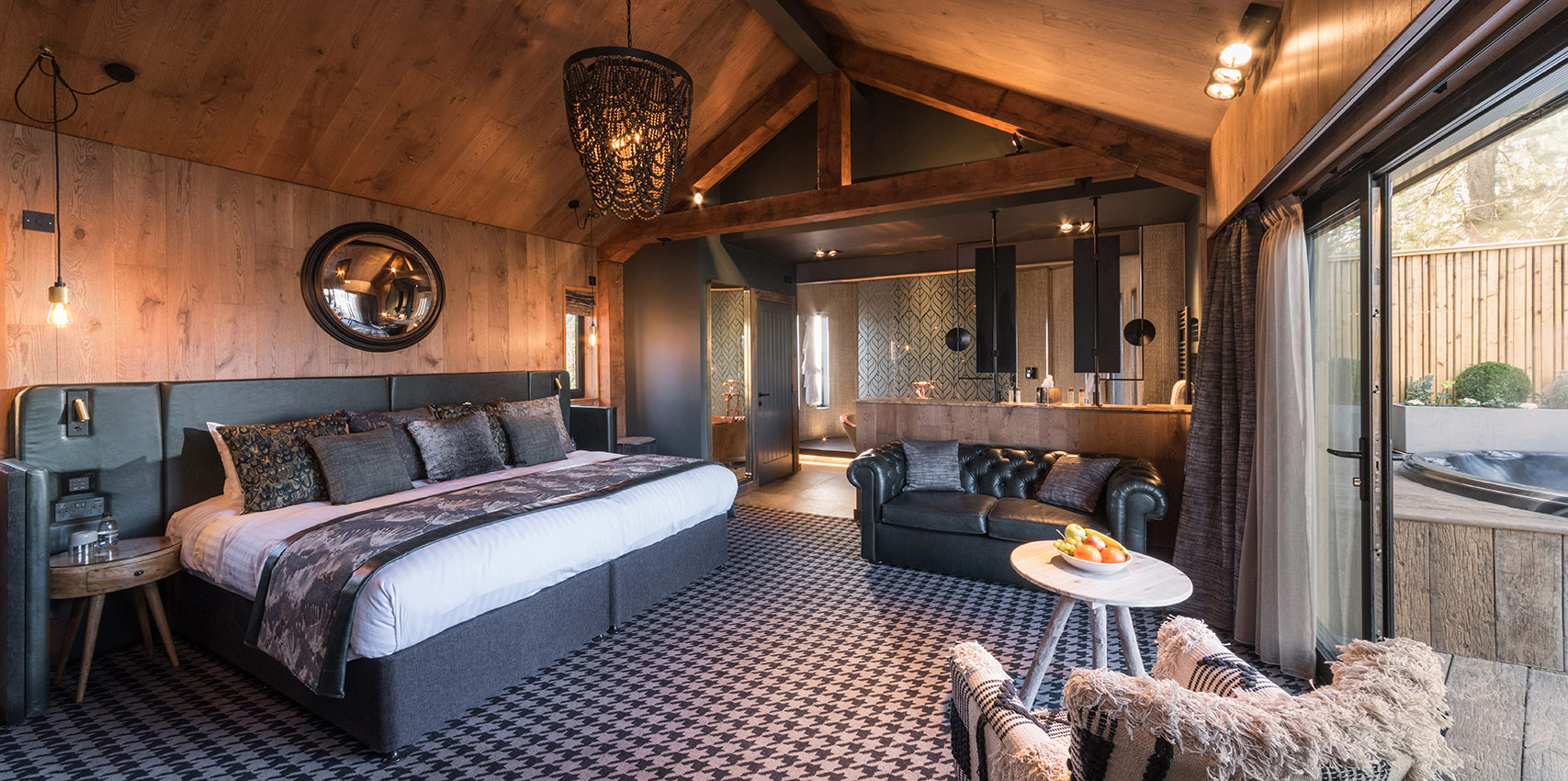 Hotel bedroom with open plan bathroom and glazed wall leading to outdoor decking