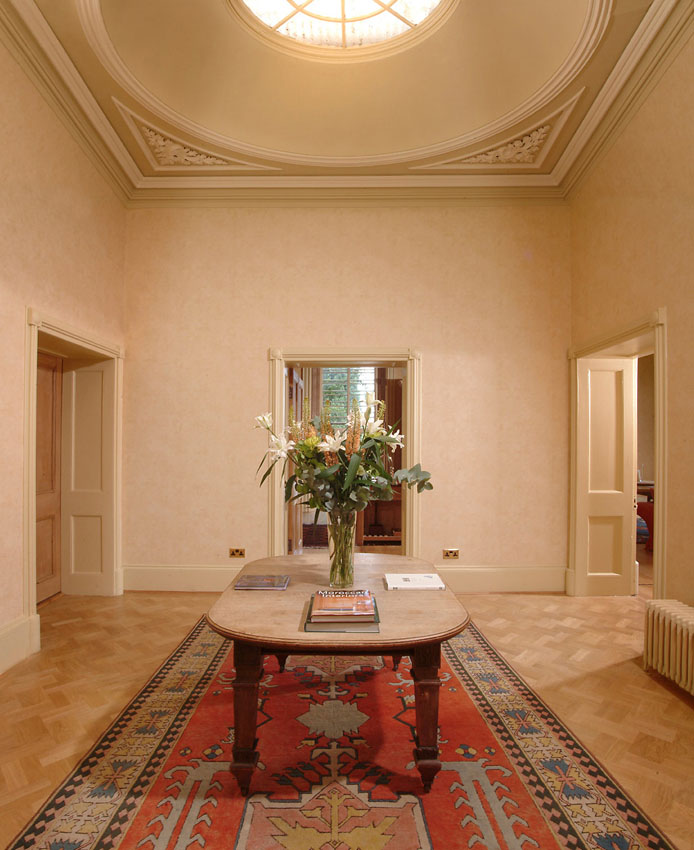 Hallway in a residential property with a round ceiling window and wooden table