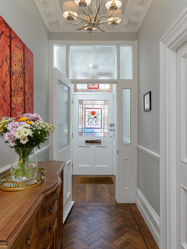 Interior of a doorway looking through a hallway with flowers and wooden furniture