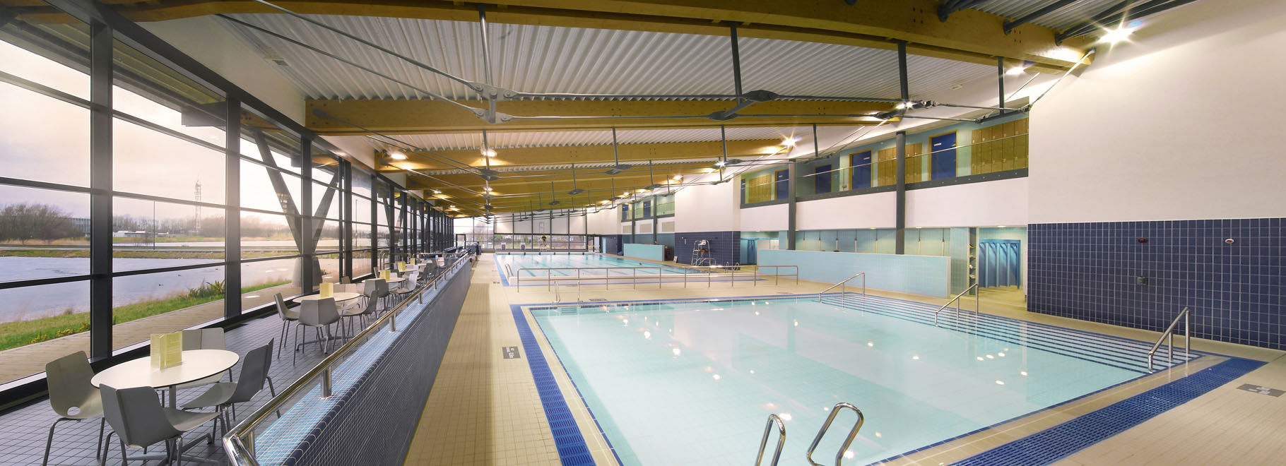 Leisure centre pool with glazed wall overlooking a lake
