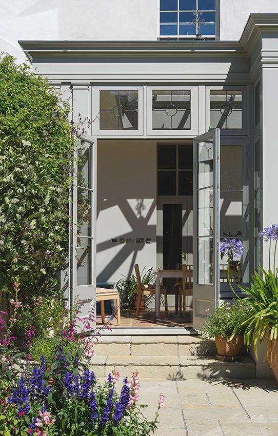 Detail view of a doorway into an orangery past plants in summer