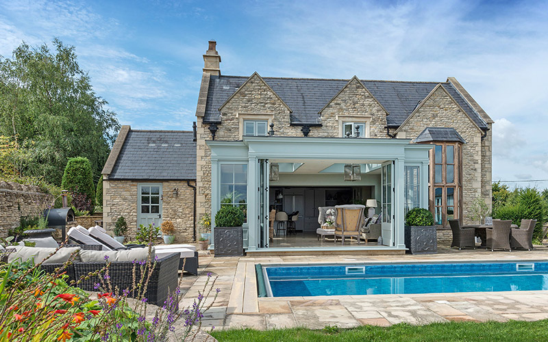 Exterior of a orengery and outdoor pool with a summer feel
