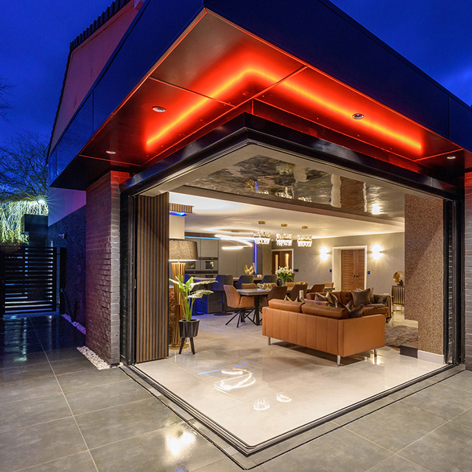 View into a residential interior space at dusk showing furniture in open plan kitchen and living space