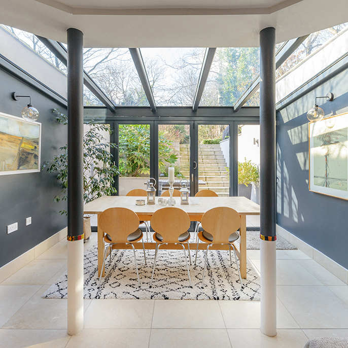Interior of a residential property looking towards a sunken garden past wooden furniture