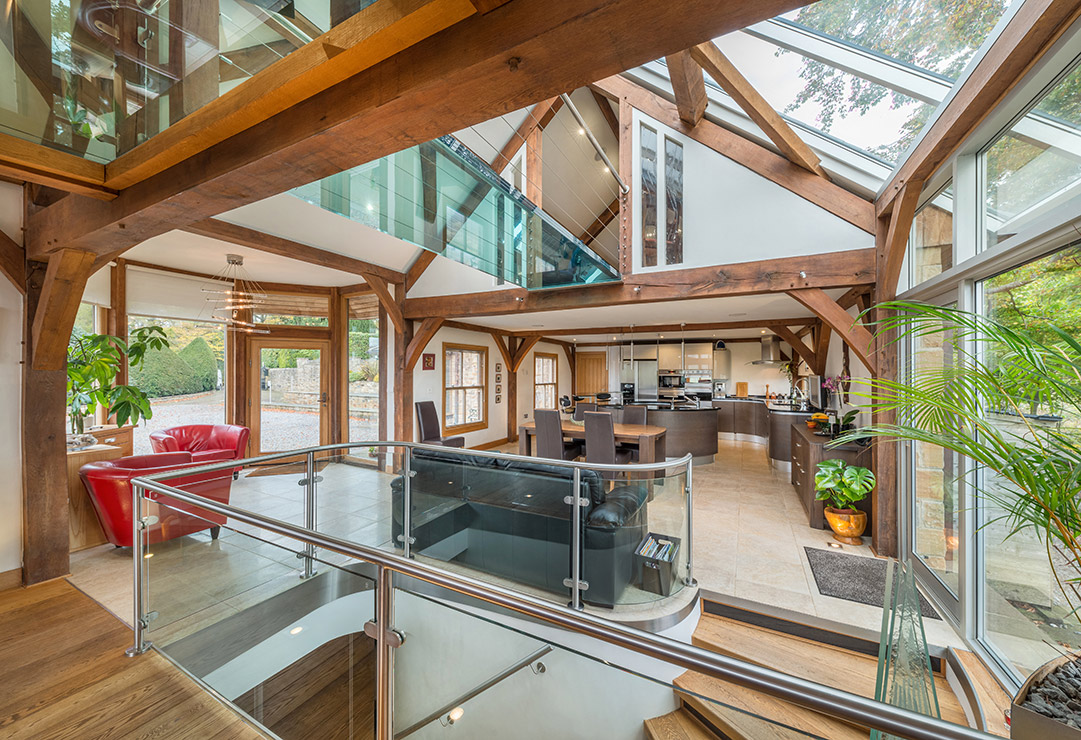 Residential property interior with high exposed roof beams and large window overlooking the gardens