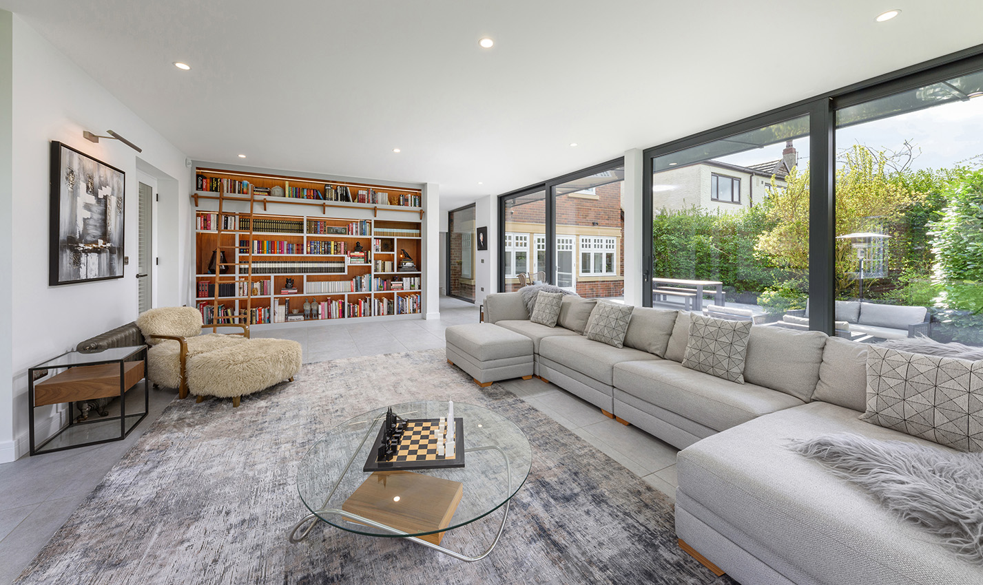 Interior of garden room with library wall and large window overlooking the garden