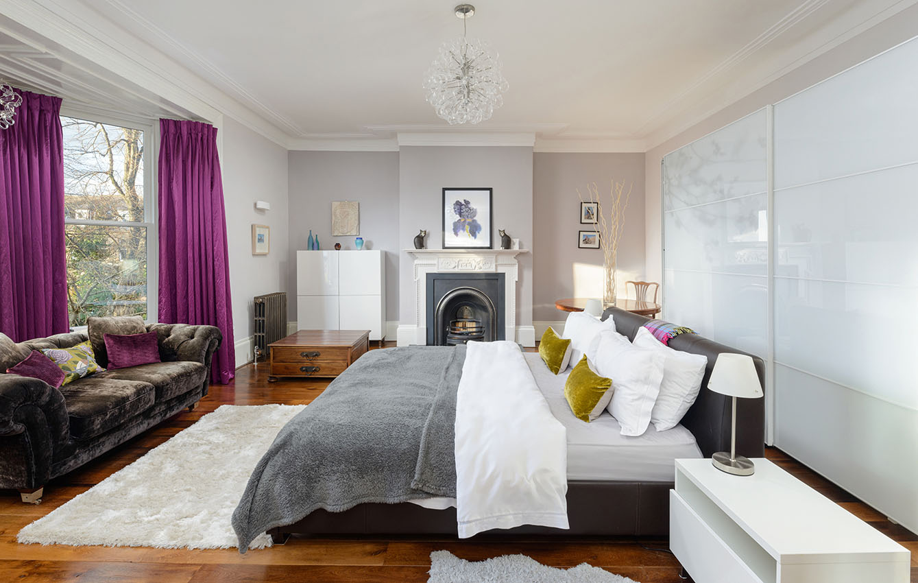 Interior of a bedroom with fireplace and views over gardens
